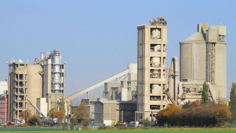 Das Bild zeigt eine Industrieanlage vor einer grünen Landschaft. 